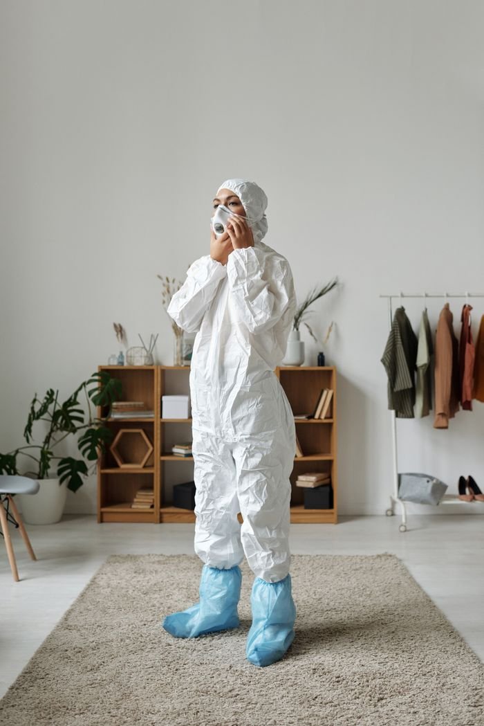 Crafting Captivating Headlines: Your awesome post title goes here Adult wearing PPE suit and mask standing indoors on carpeted floor.
